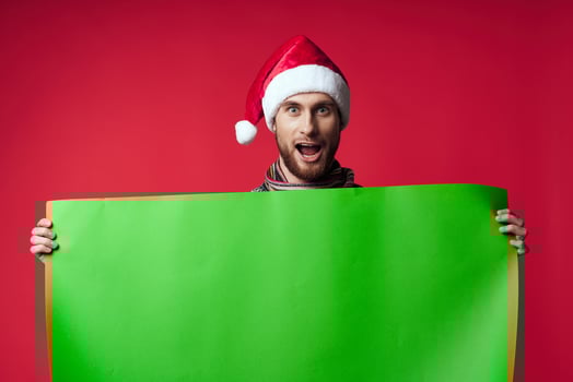 emotional man in a santa hat holding a banner holiday red background photo