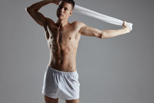 guy with a naked torso holding a towel in his hands white shorts workout motivation isolated background photo