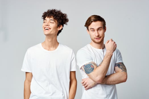 Two cheerful friends in white t-shirts stand side by side cropped view photo