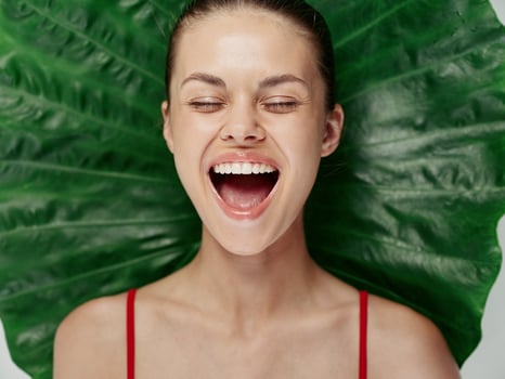 woman with closed eyes with mouth wide open fun close up palm leaf photo