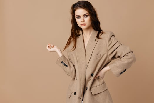 sexy woman in a coat on a beige background gestures with her hands photo