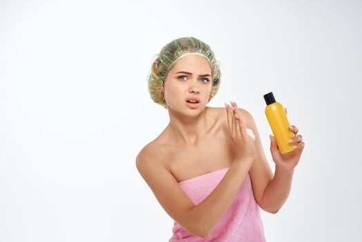 woman with unhappy facial expression in pink towel lotion skin care photo