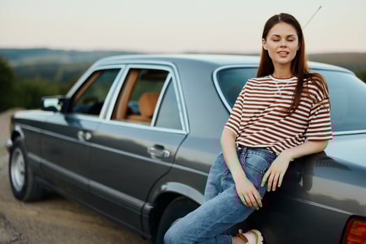 A woman driver near her retro car relaxing from the tough road and enjoying the scenery photo