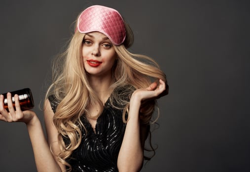 Beautiful blonde with a pink sleep mask and a bottle of beer in her hand photo