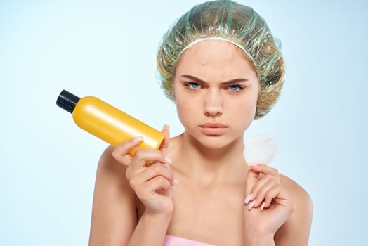 disgruntled woman wiping her face with a charge disc skin care lotion blue background photo