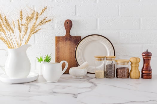 various types of kitchen utensils and utensils on a marble countertop against a white brick wall. front view. ecologically clean kitchen. photo