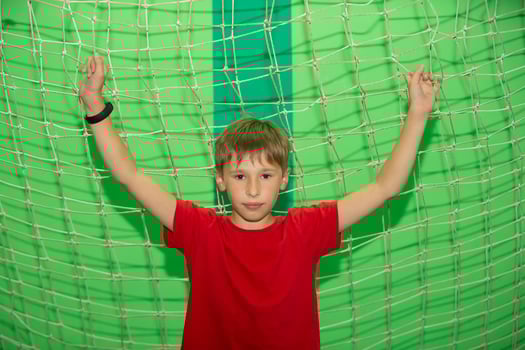 A little boy in the gym stands near the football net. photo