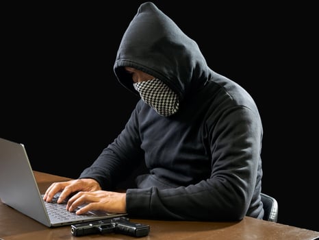 Hacker spy man one person in black hoodie sitting on a table looking computer laptop used login password attack security to circulate data digital in internet network system, night dark background. photo