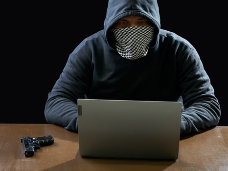 Hacker spy man one person in black hoodie sitting on a table looking computer laptop used login password attack security to circulate data digital in internet network system, night dark background. photo