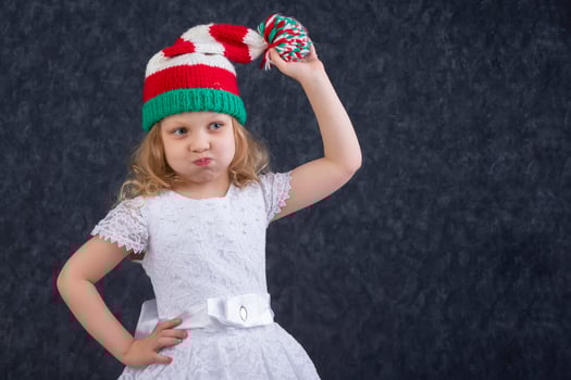 Funny little blonde in a knitted Christmas hat with a pompom. Happy beautiful child about five years old. photo