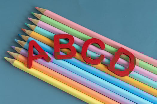 Back to school concept with assorted letters and colored pencils in pastel colors photo