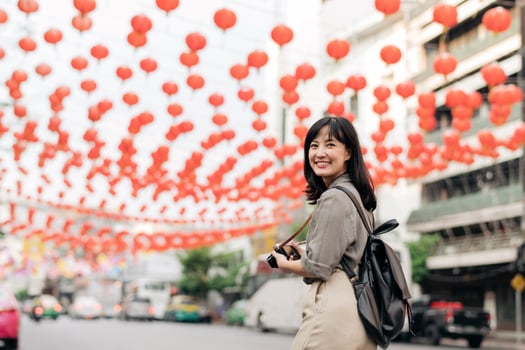 Young Asian woman backpack traveler enjoying China town street food market in Bangkok, Thailand. Traveler checking out side streets. photo