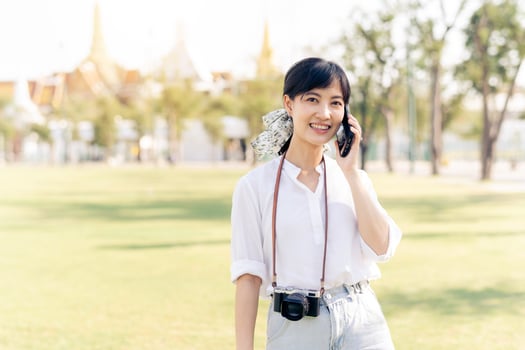 Portrait beautiful young asian woman with smartphone on summer holiday vacation trip with the grand palace in a background at Bangkok, Thailand photo