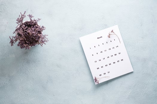 Blank sheet of the monthly calendar and a bouquet of dried flowers on the table. Time planning and organization photo