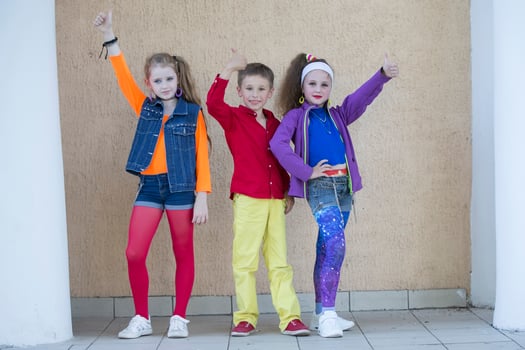 Children pose for a photo shoot. Boy and two little girls models in bright clothes are looking at the camera.
