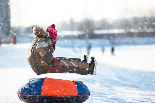 Little child on a sleigh. Child on a winter day. A boy is riding on a snow slide. photo