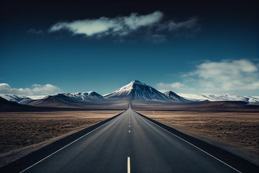 Empty asphalt road in Iceland with snow capped mountains in the background. photo