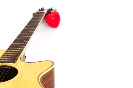 Acoustic guitar neck and red heart against white background. Love and music concept. photo
