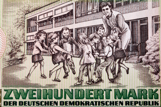 Schoolyard with eight children and a teacher from East German money photo