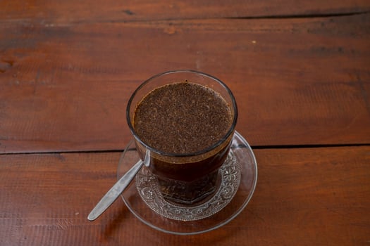 Close up photo a cup of arabica coffee with spoon from high angle. The photo is suitable to use for coffee shop background, menu poster and coffee content media.