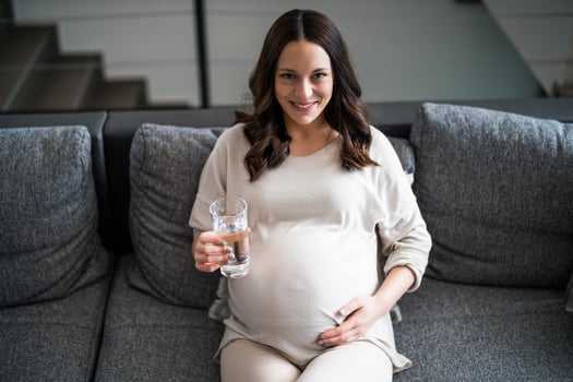 Pregnant woman drinking water at home. photo