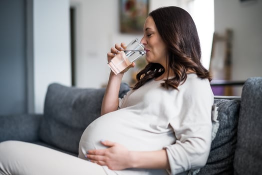 Pregnant woman drinking water at home. photo