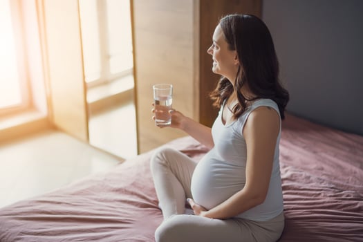 Pregnant woman drinking water at home. photo