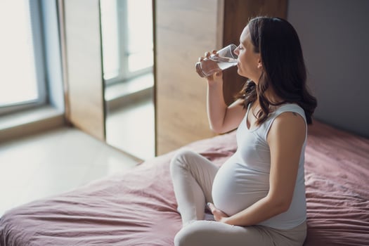Pregnant woman drinking water at home. photo
