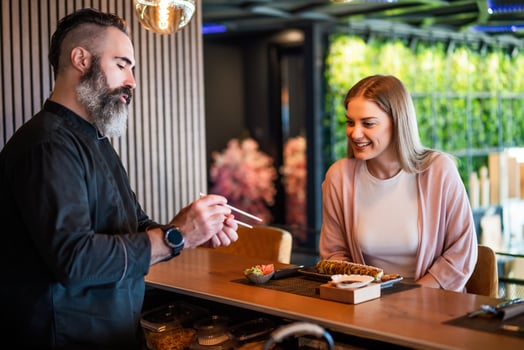 Sushi master showing a woman how to use chopsticks. photo