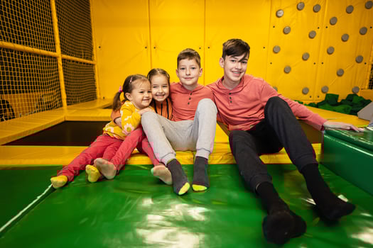 Four kids together sit at playground park. Sisters and brothers in active entertaiments. photo
