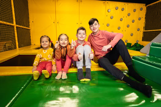 Four kids together sit at playground park. Sisters and brothers in active entertaiments. photo