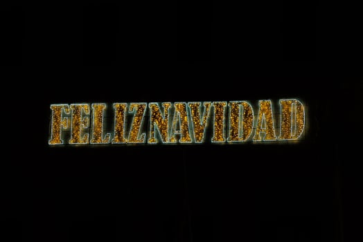 golden shiny neon inscription merry christmas on a black background in Spanish photo