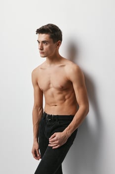 Sporty man with a naked torso on a light background and dark trousers model photo