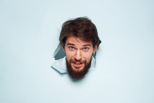 A bearded man peeps out from behind the wall dissatisfaction emotions office official photo