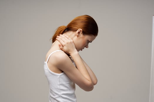 disgruntled woman holding on to the neck health problems joint light background photo