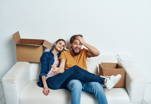 Emotional young couple on the couch with cardboard boxes interior photo