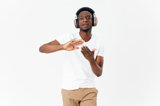 man of african appearance in headphones gesturing with his hands music lover light background photo