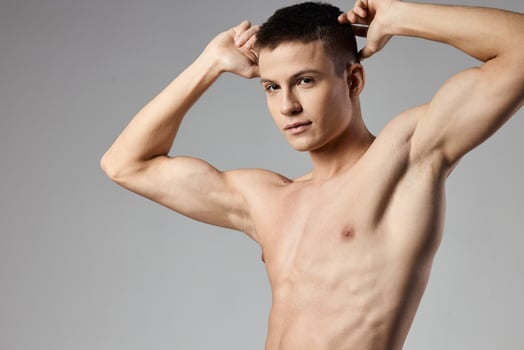 athlete with naked torso showing arm muscles on gray background cropped view of bodybuilder photo