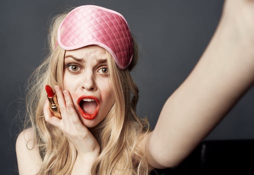 Drunk woman with lipstick on a gray background gestures with her hands photo