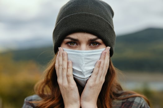 Portrait of a beautiful woman in a medical mask on nature in the mountains photo