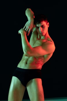 guy athlete in black shorts gesturing with his hands on a dark background cropped view photo