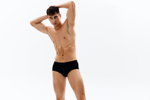 attractive man with naked muscular body in dark in shorts cropped view in light background photo