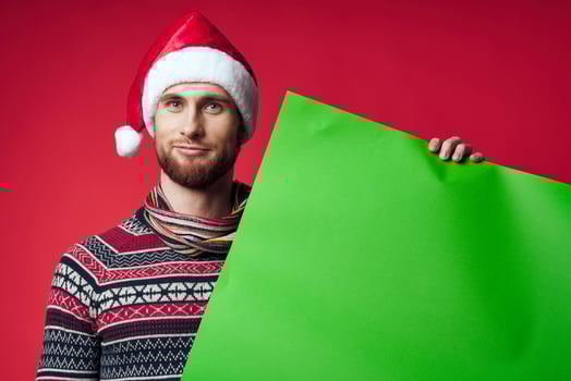 emotional man in a christmas hat with green mockup red background photo