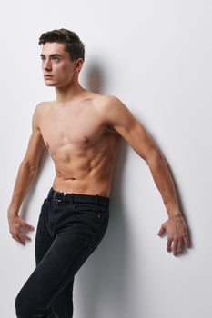 A young man with an athletic figure leaned his arms against the wall photo