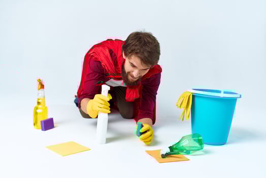 A man with cleaning supplies in a red raincoat on the floor of a home interior professional photo