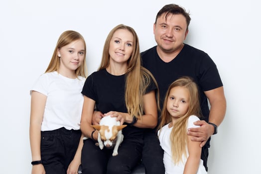 husband with wife and two daughters purebred dog family photo joy