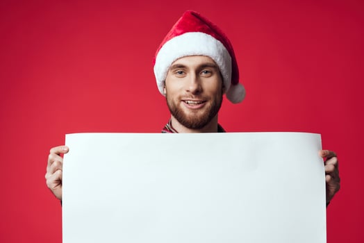 Cheerful man in a santa hat holding a banner holiday isolated background photo