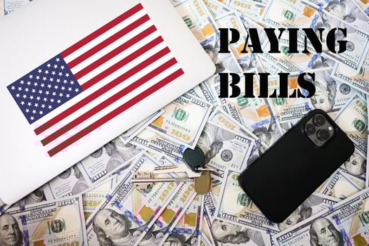 Paying bills concept. USA flag, dollar money with keys, laptop and phone background. photo