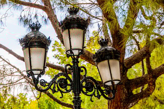 antique metal black lantern in the city against the backdrop of green trees photo