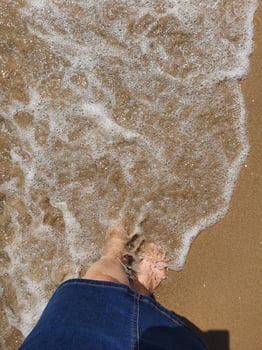 woman's  feet immersed in the sea water at the beach on a sunny warm day photo